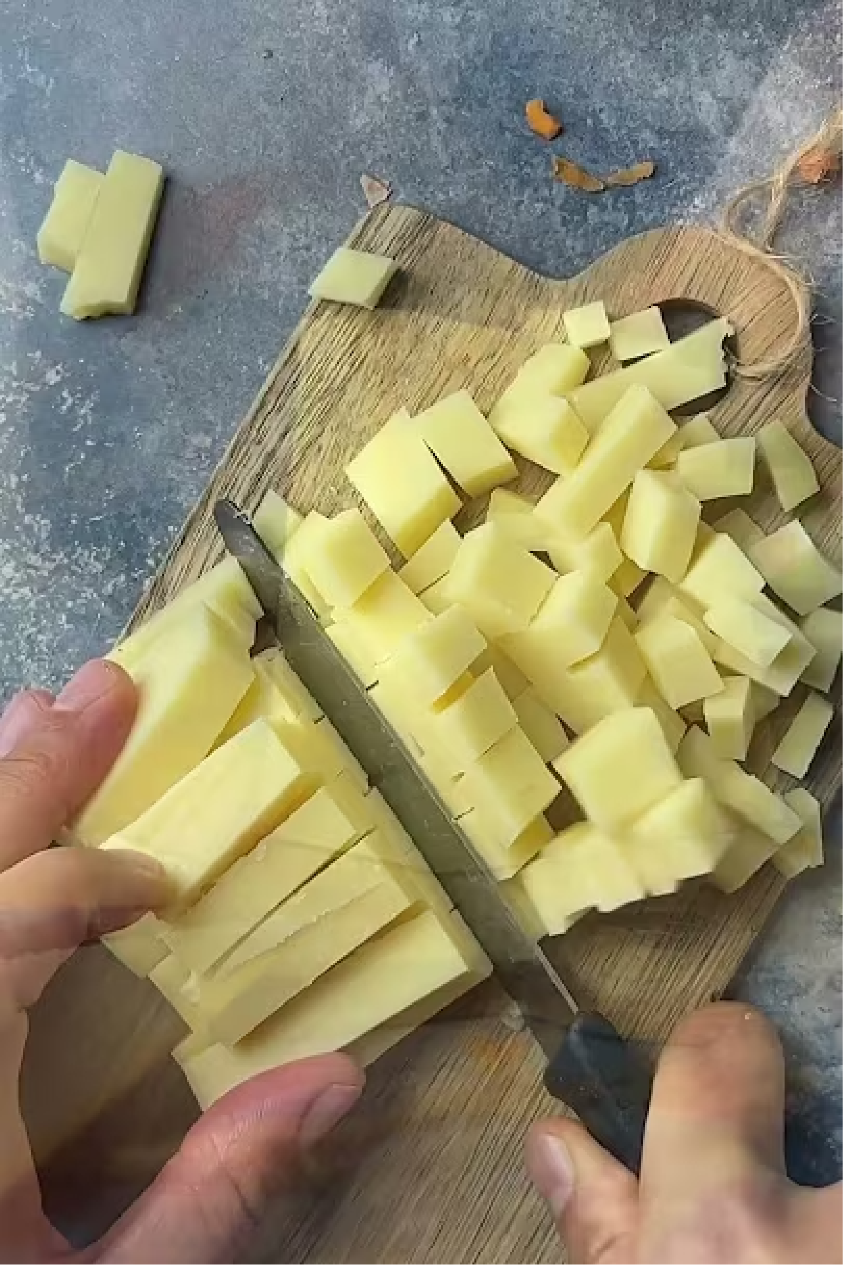 Eine Hand schneidet Kartoffeln auf einem Brett.